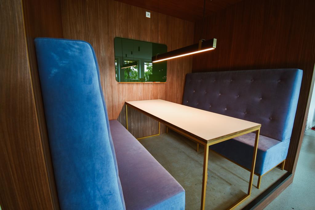 Gepolsterte Hochlehner in Blau und Violett an einem langen Tisch.
