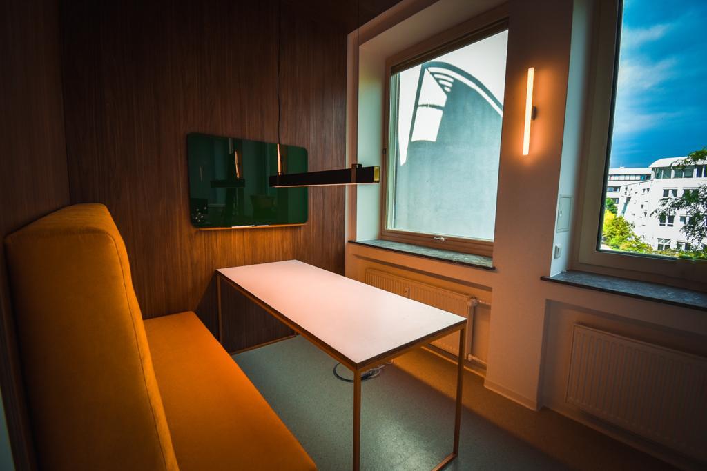 Orange gepolsterte Nische mit Tisch als Rückzugsort im offenen Raum.