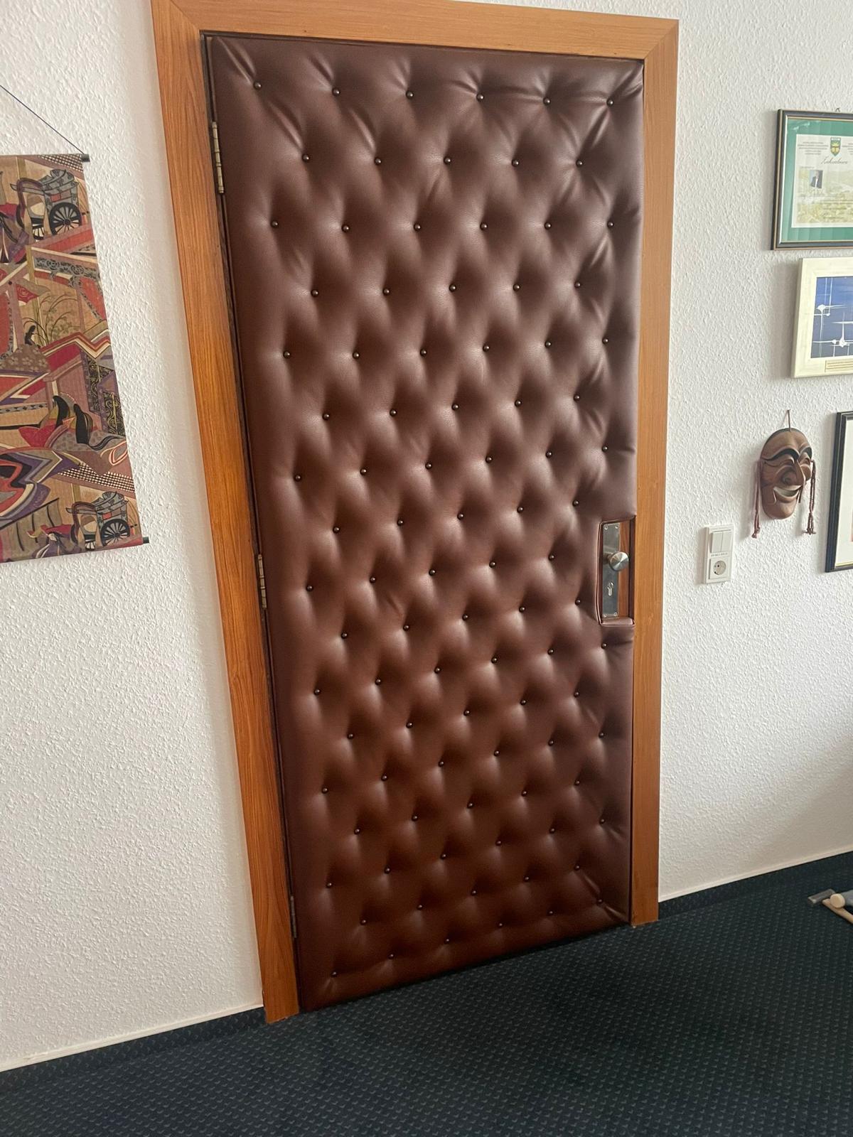 Vollflächig in brauner Kapitonage gepolsterte Bürotür mit Knopfheftung.