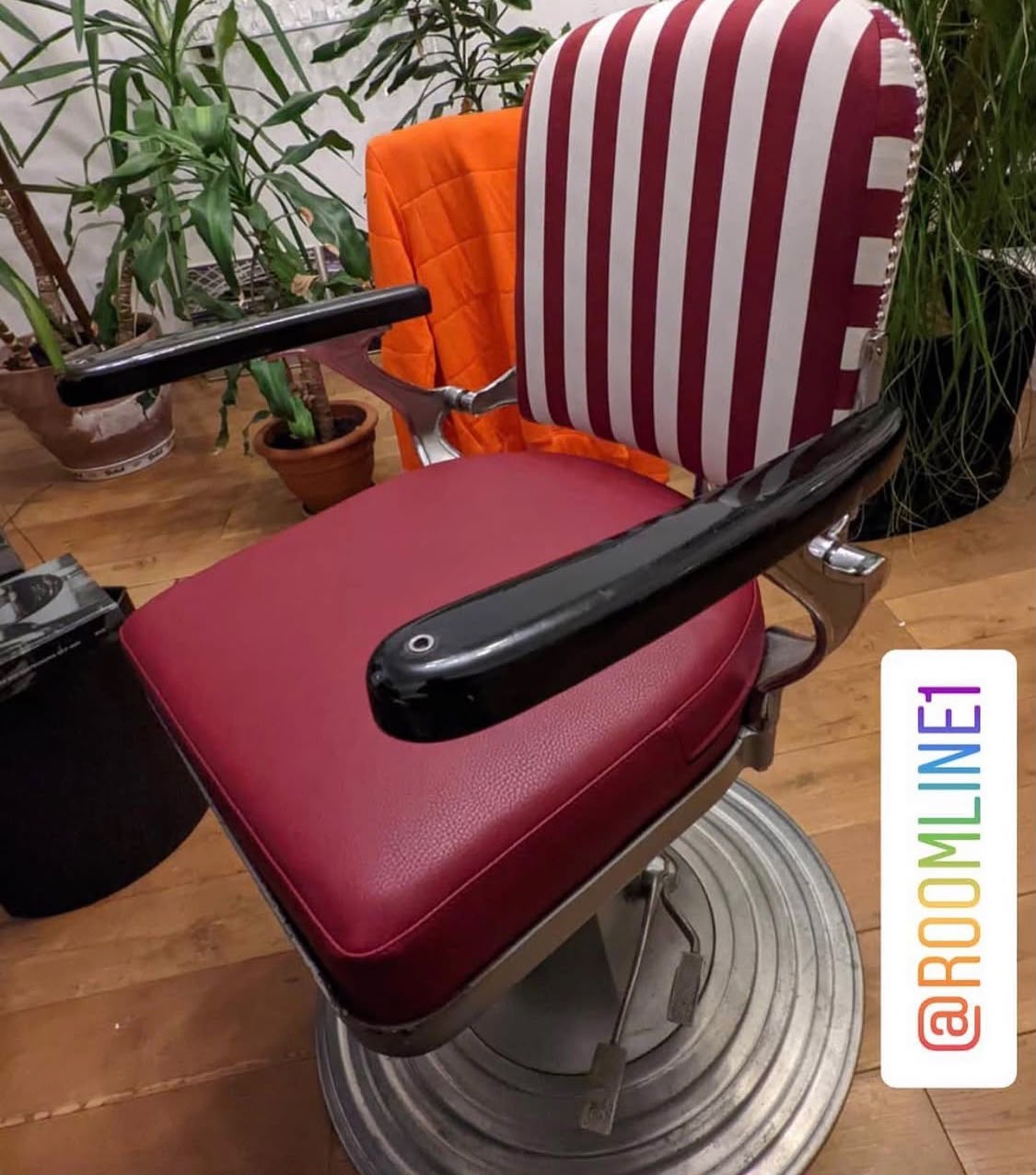 Rot-weiß gestreifte Rückenlehne mit Ziernägeln, Sitz in dunkelrotem Leder, schwarz lackierte Armlehnen am Chromgestell.