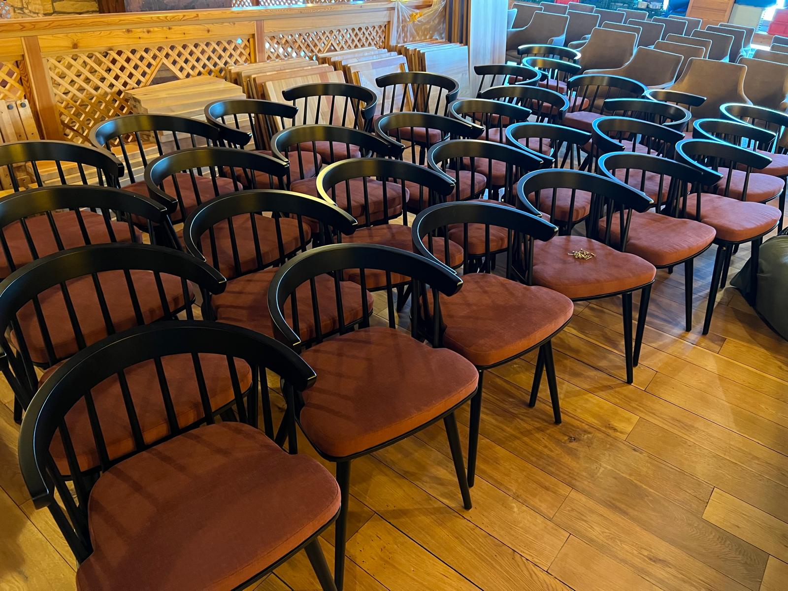 Reihen schwarzer Objektstühle mit cognacfarbenen Sitzpolstern im Saal