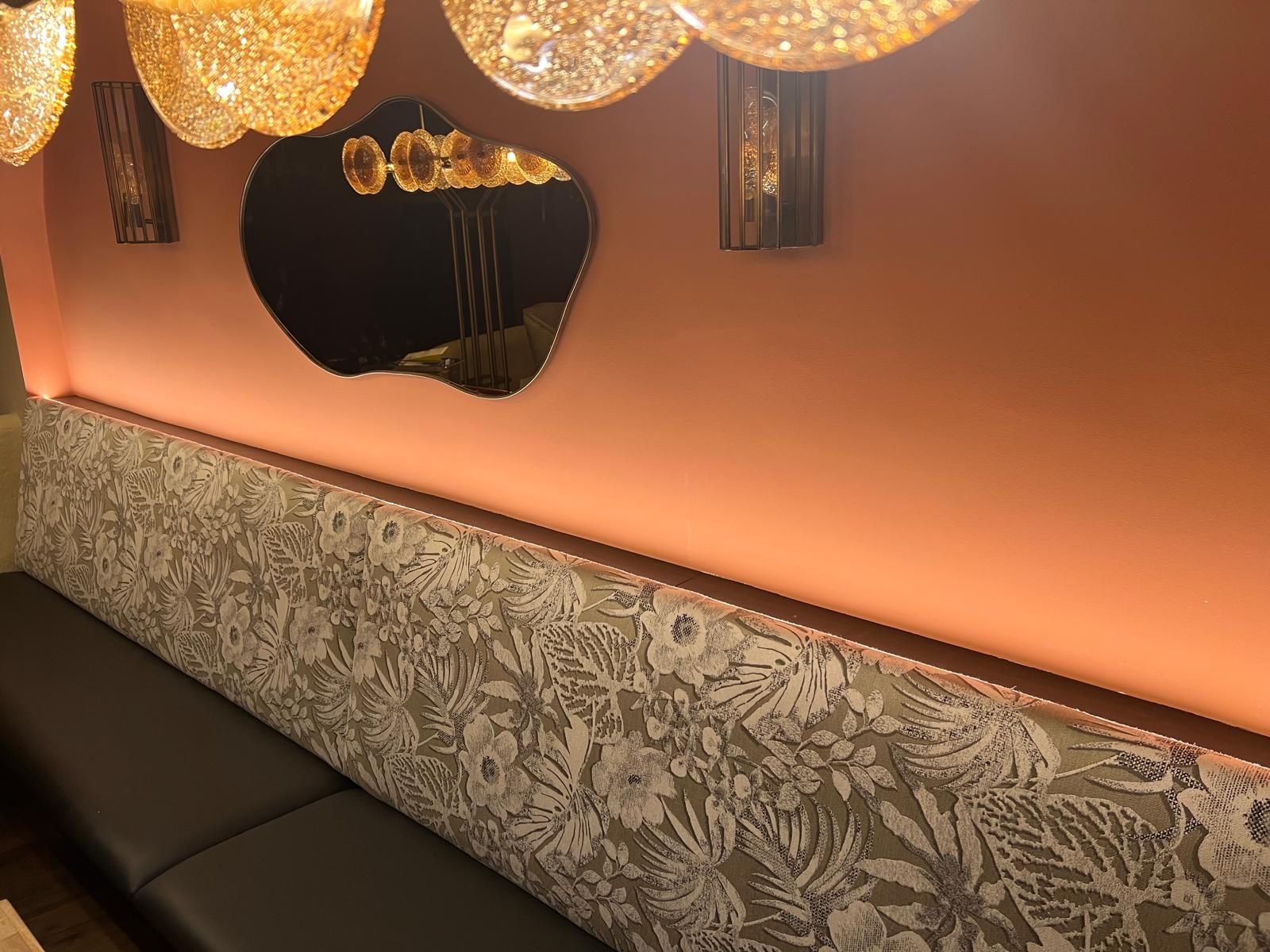 Sitzbank mit floral gemusterter Vorderseite und dunkler Sitzfläche im Gastraum.