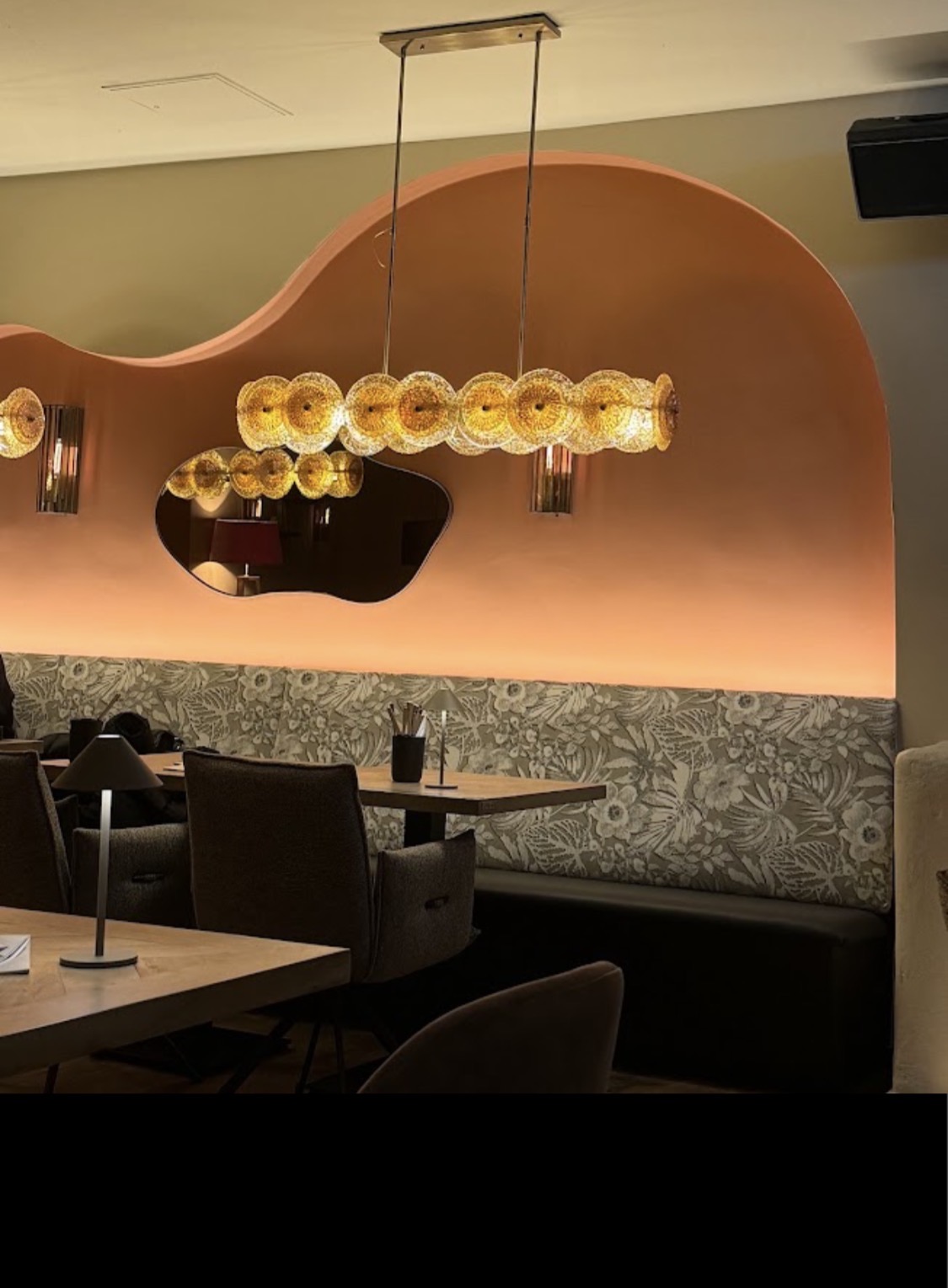 Sitznische im SOMA unter der geschwungenen Terrakotta-Wand, Bank mit floralem Bezug in Grün und Beige.